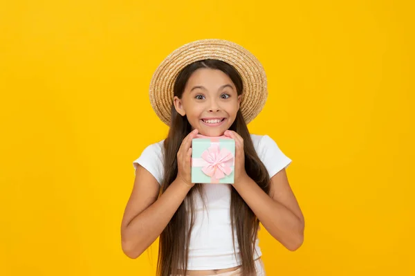 Pleased teen kid hold present box on yellow background — Zdjęcie stockowe