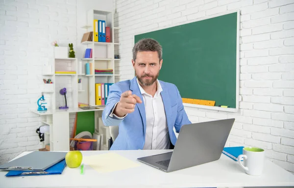 Profesor de escuela seria en el aula con ordenador en pizarra. dedo índice — Foto de Stock