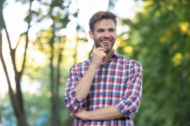 Dışardaki kareli gömlekli genç adam gülümsüyor.