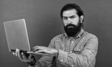 Bilgisayarda çalışan olgun bir öğretmen. Sınıfta dizüstü bilgisayarlı kaba sakallı bir adam çalışıyor. Online sınav için hazırlanın. Özel ders üzerine üniversite hocası. Okula dönüyorum. çevrimiçi kayıtdışı eğitim