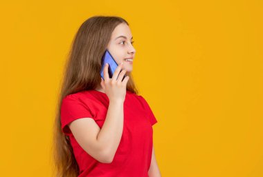 Çocuk sarı arka planda akıllı telefondan konuşuyor.