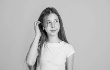 Saç güzelliği ve sağlık. Şirin güzelin uzun esmer saçları var. Moda tarzı. Sarı arka planda neşeli bir kız. Sıradan beyaz tişörtlü genç bir çocuk. çocukluk mutluluğu