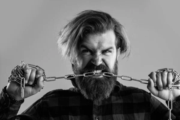 Жестокий бородатый мужчина кусает стальную цепь с сильными зубами, исправляет укус — стоковое фото