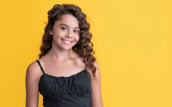 Child smile with long brunette frizz hair on yellow background — Stock fotografie