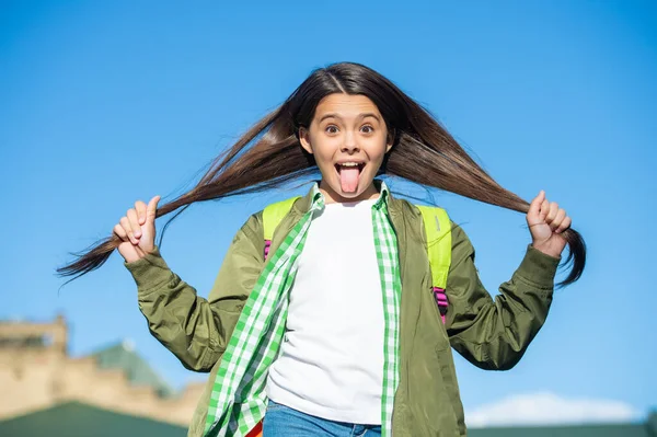 Смішна шкільна дитина з рюкзаком тримає волосся — стокове фото