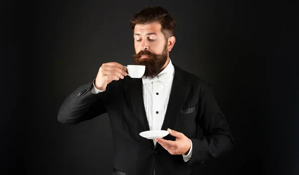 穿着燕尾服的男人带着咖啡杯打领带。穿正装的绅士在黑色的背景上闻到咖啡的味道 — 图库照片