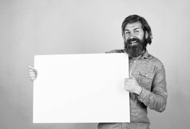 look here. happy bearded man. brutal caucasian hipster hold paper shit, copy space. human emotions. unshaven guy with groomed long hair. barbershop and hairdresser. male beauty and fashion