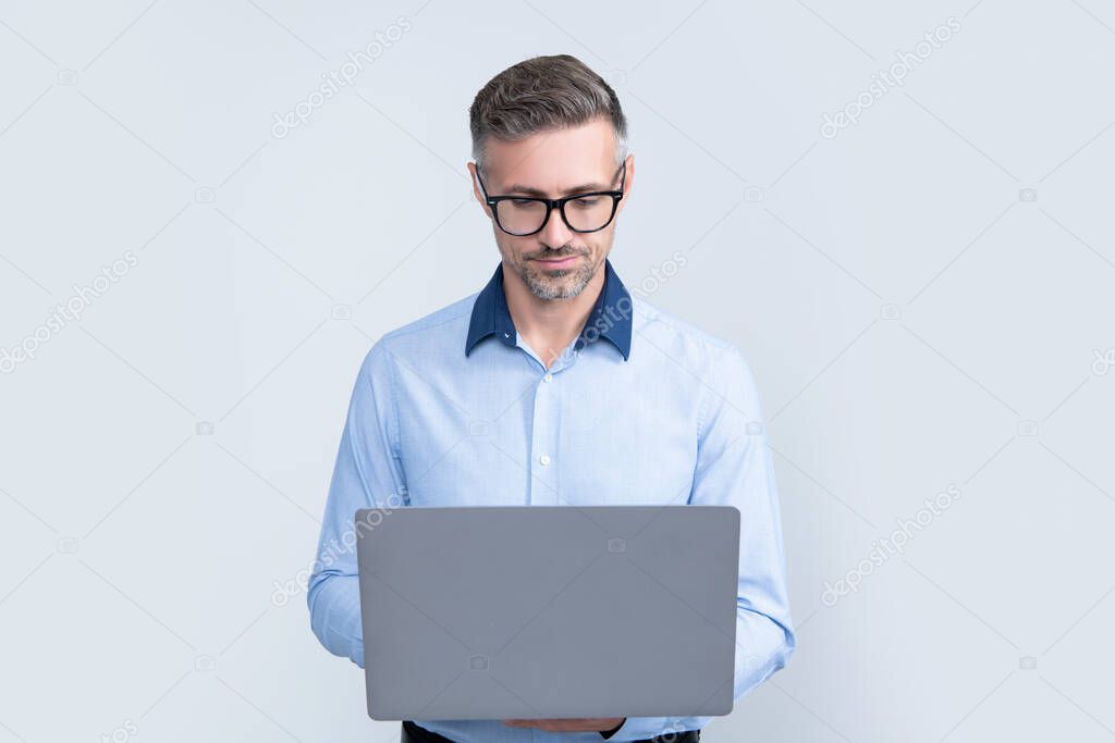 mature office worker in eyeglasses working on computer on grey background