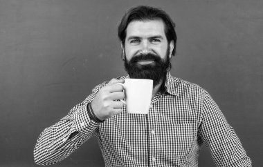 Mutlu adam sabah kahvesini yeşil arka planda fincandan içiyor.