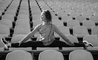 İyi esneme hareketleri. esnekliği böl. Beden eğitimi dersinde çocuk eğitimi. Kız antrenmandan önce geriniyor. Jimnastikçi yarışmaya hazırlan. Sporcu stadyum tribününde ısınıyor.