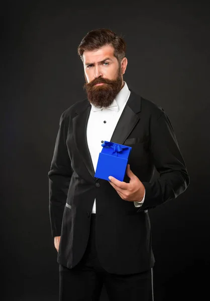 Serious man in tuxedo bow tie formalwear on black background with box. valentines day — стоковое фото