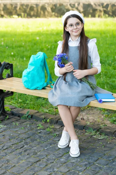 Niño feliz en gafas relajarse en el banco del parque con flores. día de las mujeres — Foto de Stock