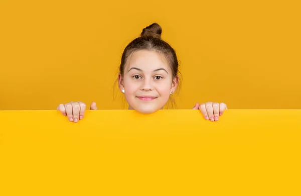 Happy girl behind blank yellow paper with copy space for advertisement — Foto Stock
