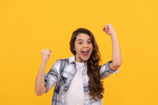 Glad teen kid in checkered shirt with long curly hair on yellow background — Stockfoto
