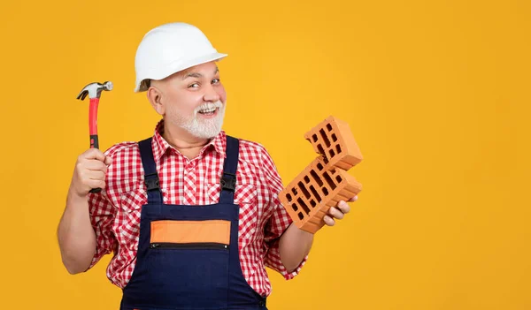 Felice vecchio lavoratore in casco su sfondo giallo — Foto Stock