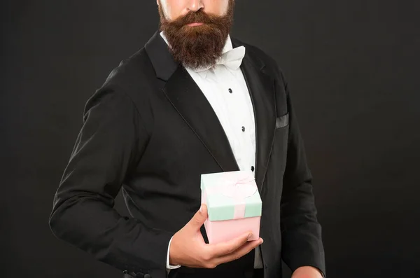 Copped man in tuxedo formalwear on black background with box for mens day — Fotografia de Stock