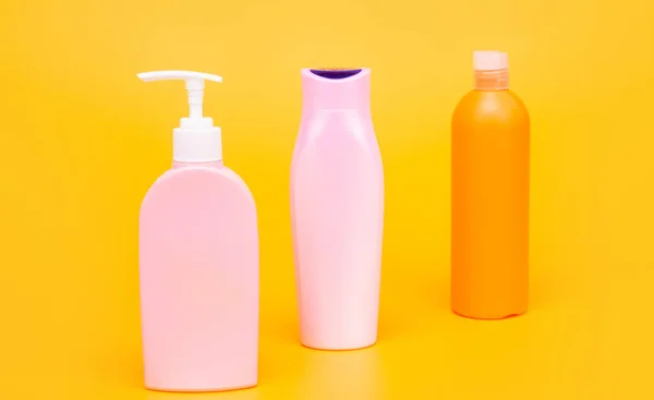 Beauty packaging. Cosmetic bottles yellow background. Toiletry bottles in row — Zdjęcie stockowe