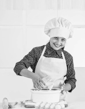 Çalışıyor. Sağlıklı beslenme ve yaşam tarzı konsepti. Kız un ve yumurtadan hamur yapıyor. Diyet ve sağlık. Aşçılık okulu. Geleneksel mutfak. Çocuk mutfakta yemekle eğleniyor. Çocuk ve fırın