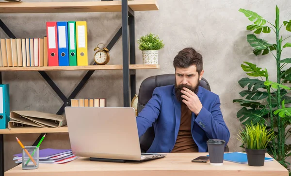 Concentrated bearded businessman work on laptop in the office, professional occupation — Zdjęcie stockowe