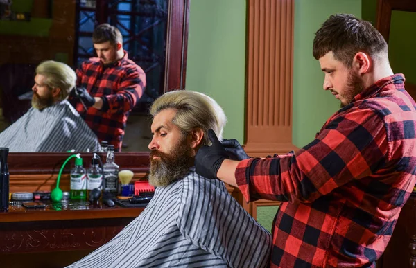 Lifestyle. master barber does the hairstyle and styling with dryer. Concept Barbershop. Young hipster man with beard cutting his hair in a barbershop. Professional hairdressing work. Young and free — Foto Stock