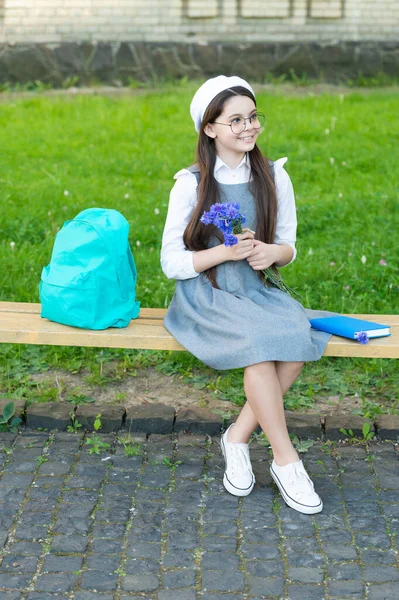 Happy child in glasses relax on park bench with flowers. 8 march — Fotografie, imagine de stoc