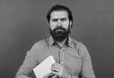 Edebiyat ve okuma. gayri resmi eğitim. Erkek öğrenci ders sırasında sınıfta oturur. Sınavı geç. Konuyu öğrenmek. Okula dönüyorum. Öğretmenler günün kutlu olsun. Sakallı vahşi adam kitap tutuyor.