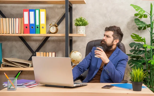 Pondering mature entrepreneur working on computer with coffee at office, modern life — kuvapankkivalokuva