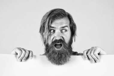 Sakallı, şık saçlı, beyaz tenli hippi elinde fotokopi alanı ve pazarlaması olan kağıt pankart tutuyor.