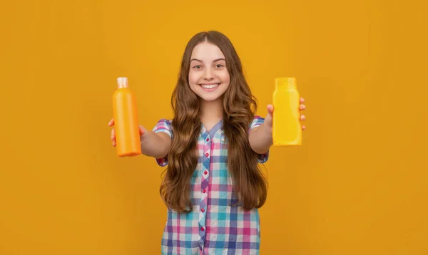 Весела дитина з пляшкою кондиціонера на жовтому фоні — стокове фото