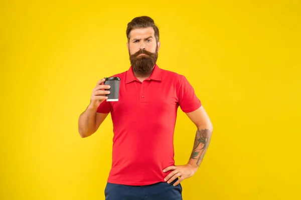 Serious bearded guy in casual red tshirt holding coffee cup yellow background, takeaway — Stock Fotó