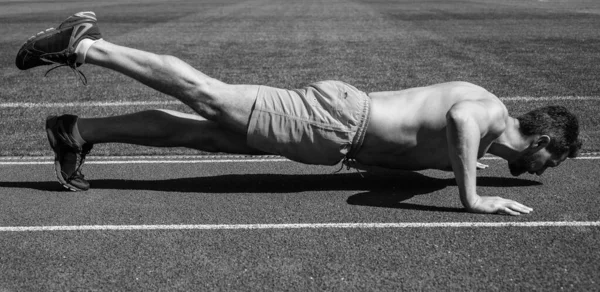 Atleet man doet push-ups staan in plank in outdoor stadion, sport — Stockfoto