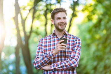 Kahve bardağıyla damalı gömlekli mutlu genç adam.