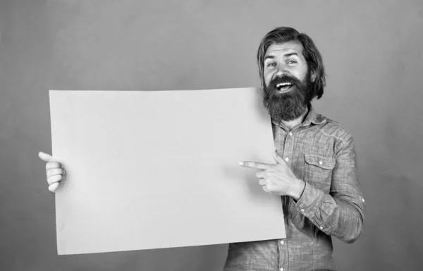 Look over there. brutal caucasian hipster hold paper shit, copy space. human emotions. unshaven guy with groomed long hair. barbershop and hairdresser. male beauty and fashion. happy bearded man — Zdjęcie stockowe