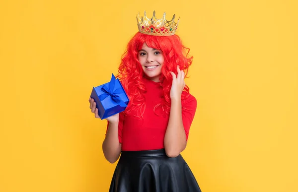 Happy kid in crown with present box on yellow background — Foto Stock