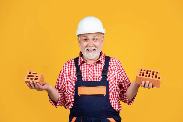 Felice uomo anziano lavoratore in cappello duro su sfondo giallo — Foto Stock