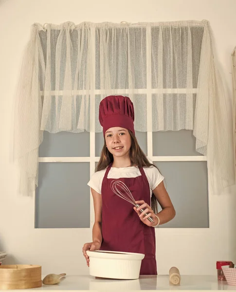 부엌에서 굽는 작은 소녀. 아이 요리사가 음료수와 함께 요리를 합니다. 아이들은 집에서 건강에 좋은 음식을 준비하고 요리용 유니폼을 입습니다. 집안일과 집안일을 돕는 일. 어린 시절의 발 달 — 스톡 사진