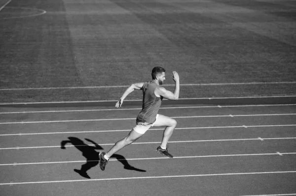 Atlético musculoso hombre corriendo en pista de carreras en el estadio al aire libre, terminar — Foto de Stock