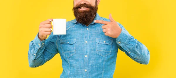 Feliz hombre vista de la cosecha señalando el dedo en la taza de café fondo amarillo, espacio de copia —  Fotos de Stock