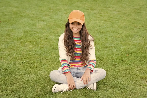 Feliz idade escolar feminino criança sorriso sentado na grama verde, menina — Fotografia de Stock