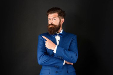 serious man in tuxedo bow tie. bride groom in formalwear pointing finger on copy space.
