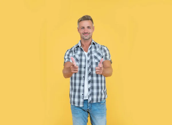 Happy mature man with grizzle hair on yellow background. pointing finger — Foto de Stock