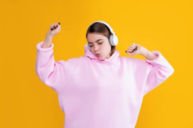 Mutlu genç kız sarı arka planda kulaklıkla müzik dinliyor.