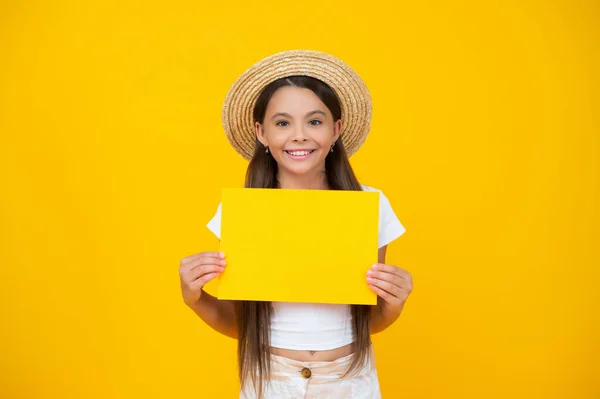 Cheerful teen girl hold empty advertisement paper with copy space on yellow background — 스톡 사진