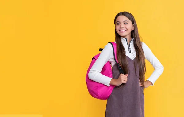 Cheerful child with school bag on yellow background — Stockfoto