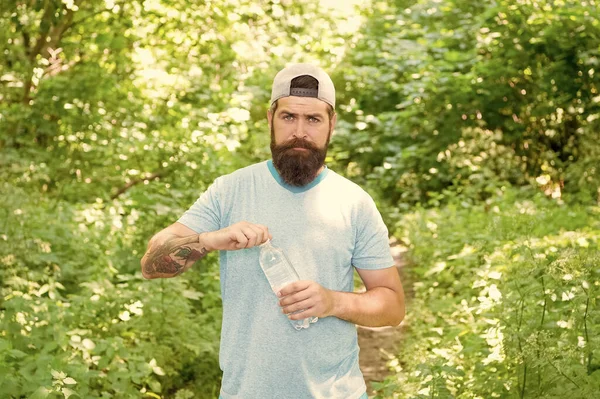 Érett szakállas férfi szakállas nyári ruhák nyitott vizes palack erdőben, edzés után — Stock Fotó