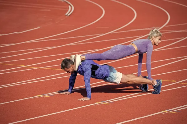 Pompare i muscoli. uomo e donna atletici in piedi tavola. allenatore maschio e femmina — Foto Stock