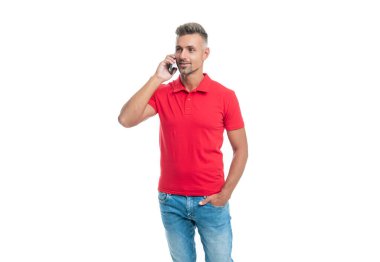 Kırmızı tişörtlü adam beyaz arka planda cep telefonuyla konuşuyor.