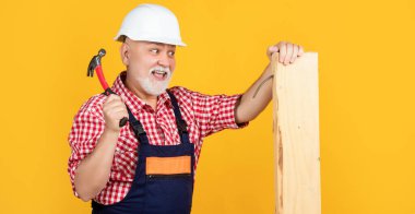 happy aged man woodworker in helmet on yellow background