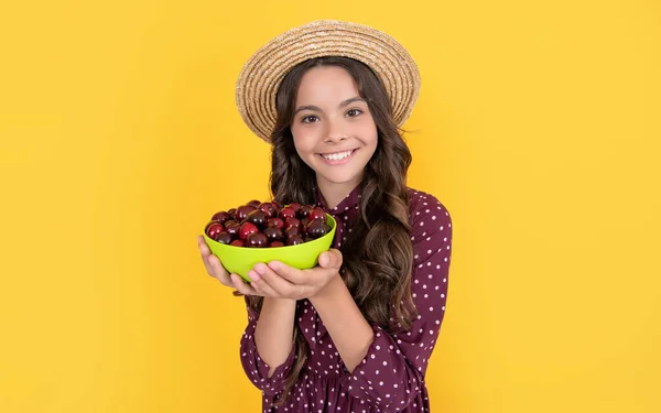 Happy teen child hold cherry bowl on yellow background — Fotografia de Stock