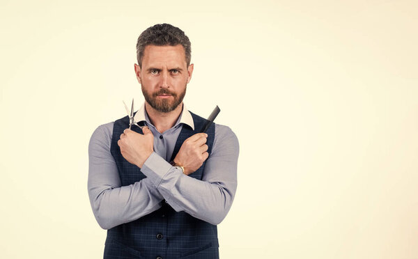 красивый мужчина держит расческу и парикмахерские ножницы, копировальное пространство, парикмахерскую